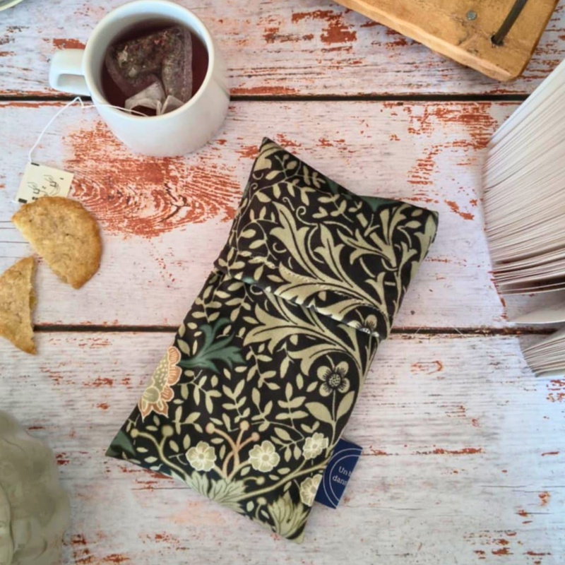 Bouillotte sèche aux graines de lin avec housse déhoussable motif floral, coussin chauffant naturel posé sur une table en bois, accessoire bien-être cocooning