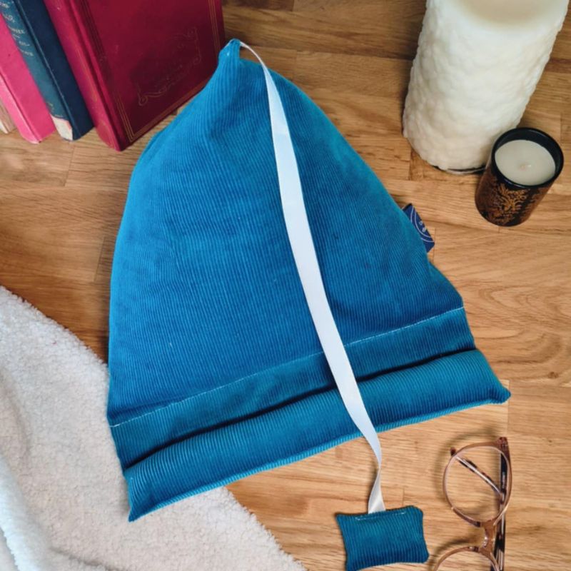 Coussin de lecture berlingot Pattes de Velours bleu roi en velours côtelé avec ruban marque-page, utilisé comme support ergonomique pour livre dans un coin lecture cosy.